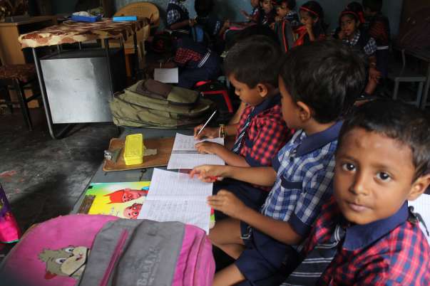 Children in blue uniforms writing together at classroom desks