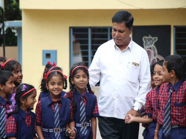 Schoolchildren standing together with a member of the school community outside the school